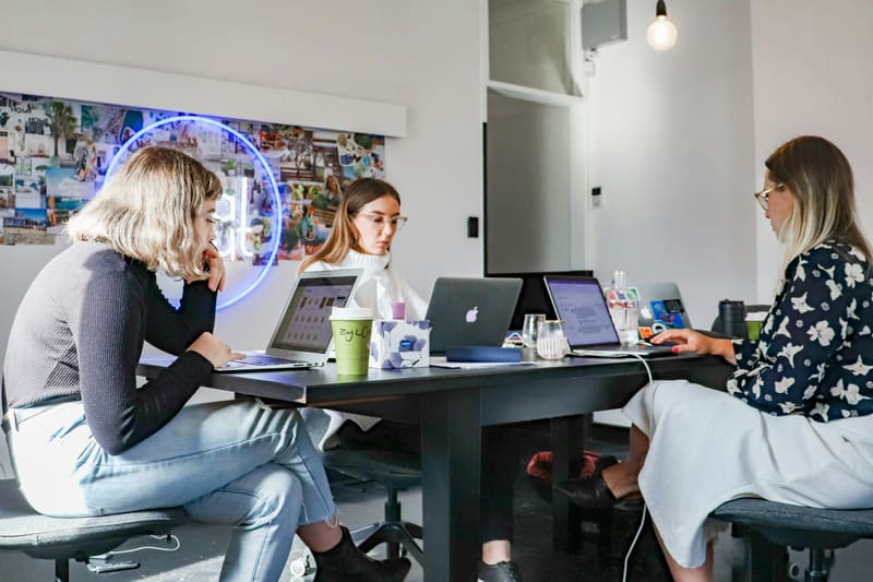 Marketing team collaborating around laptops in a bright office