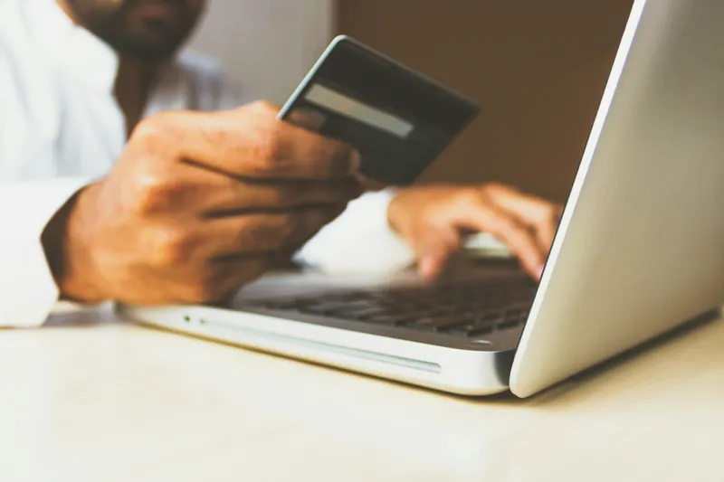 Person at laptop holding a credit card